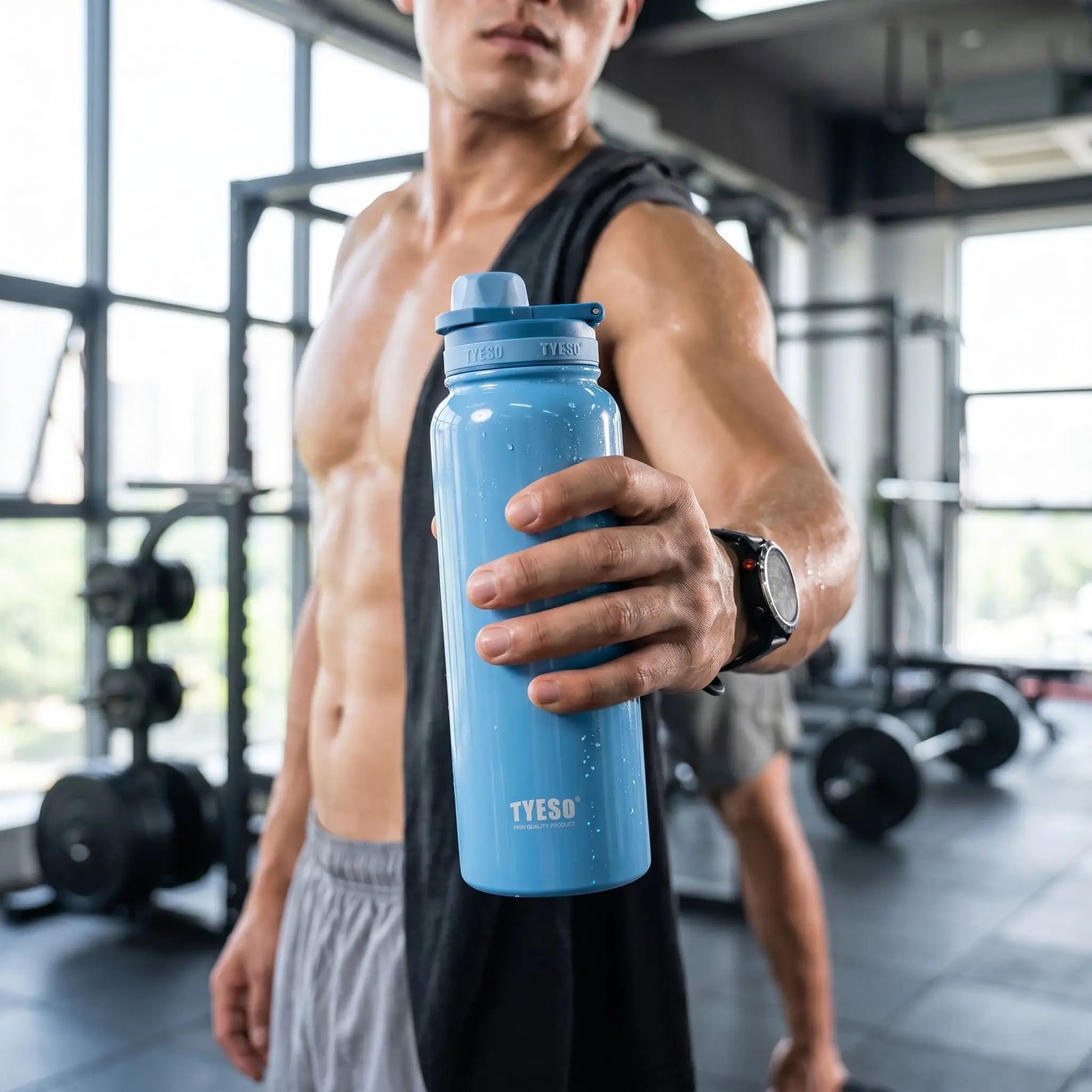 un homme dans une salle de sport avec une gourde isotherme
