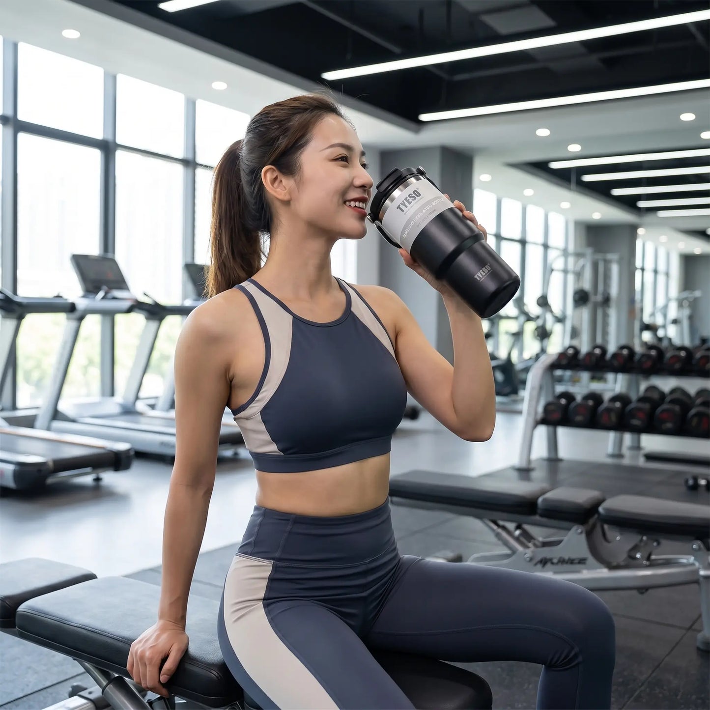 une femme au gym bois avec la gourde isotherme